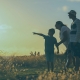 A boy and his parents. The boy is pointing off into the distance.